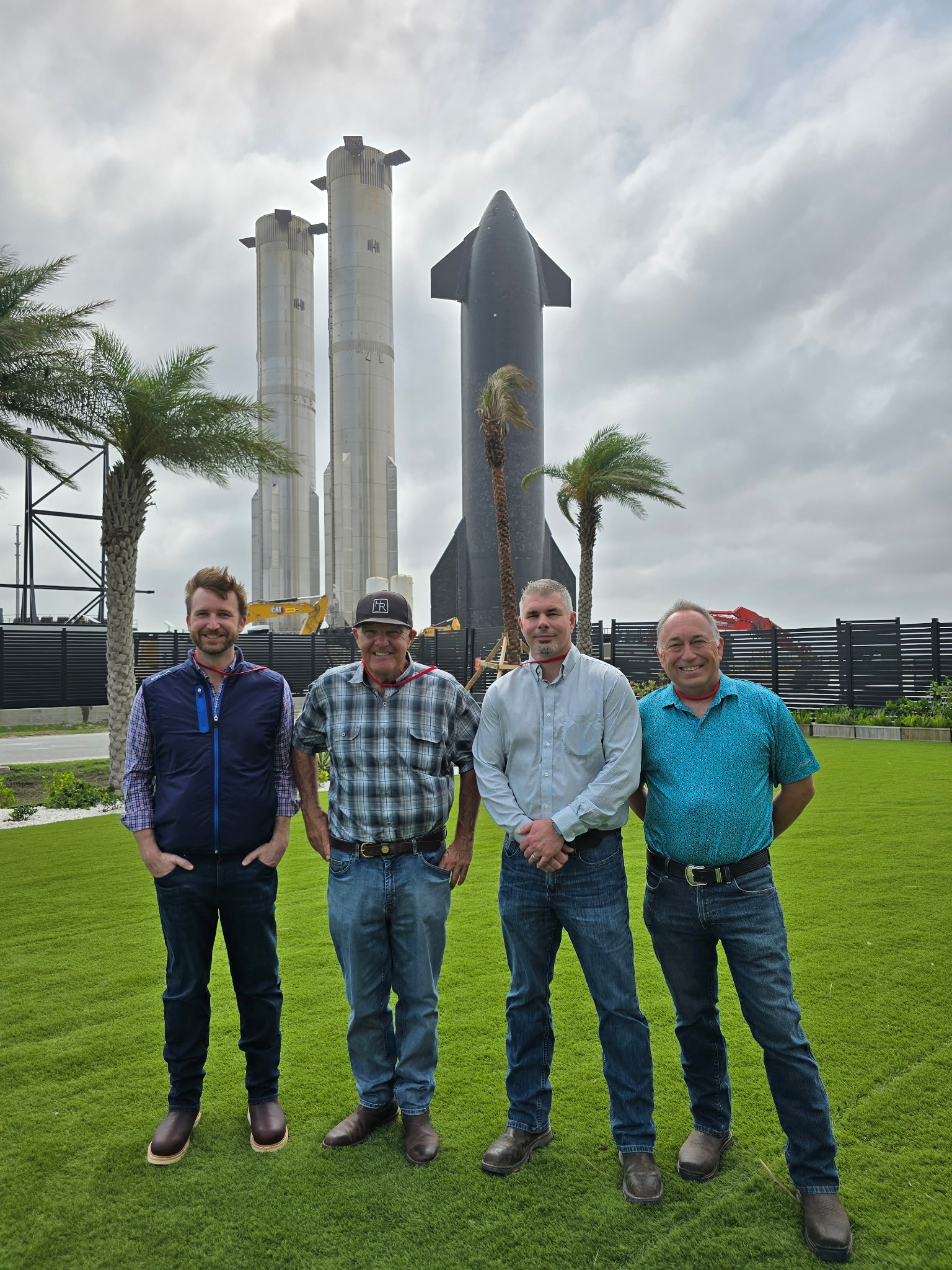 Four of Coastal Plains Trucking leadership team stand outside of SpaceX rocket.